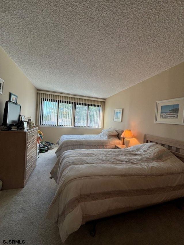 carpeted bedroom featuring vaulted ceiling and a textured ceiling