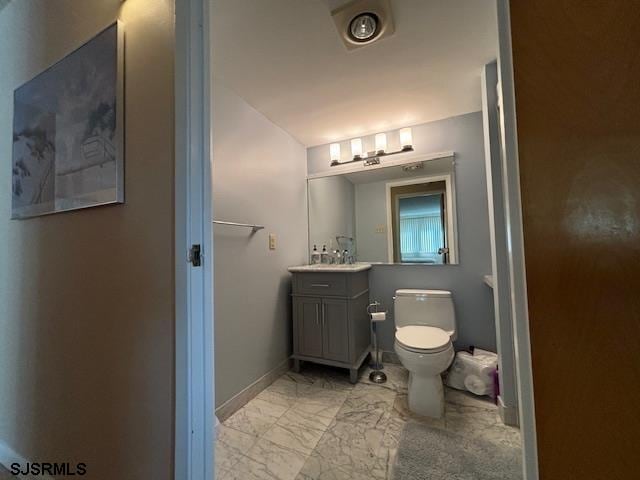 bathroom featuring marble finish floor, baseboards, vanity, and toilet