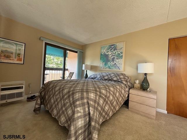 bedroom with access to exterior, a wall mounted air conditioner, carpet flooring, and baseboards