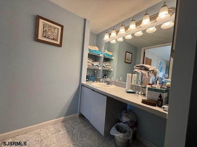 bathroom with marble finish floor, vanity, and baseboards