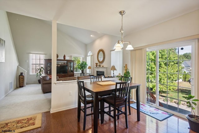 dining space with dark hardwood / wood-style flooring, an inviting chandelier, and vaulted ceiling