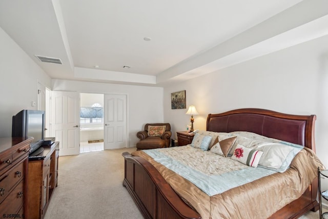 carpeted bedroom with connected bathroom and a tray ceiling