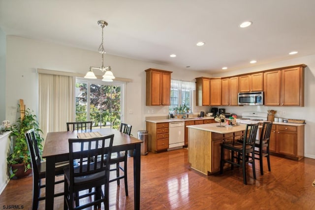 kitchen with a healthy amount of sunlight, a center island, white appliances, and dark hardwood / wood-style flooring