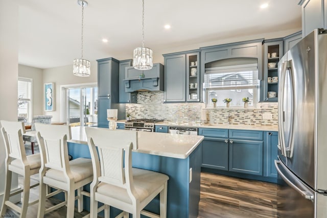 kitchen with appliances with stainless steel finishes, backsplash, hanging light fixtures, extractor fan, and dark hardwood / wood-style floors