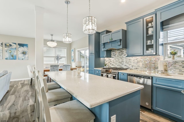 kitchen with appliances with stainless steel finishes, a center island, plenty of natural light, and hanging light fixtures