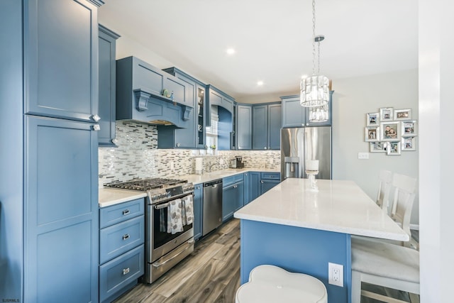 kitchen with dark hardwood / wood-style flooring, a kitchen island, blue cabinetry, pendant lighting, and stainless steel appliances