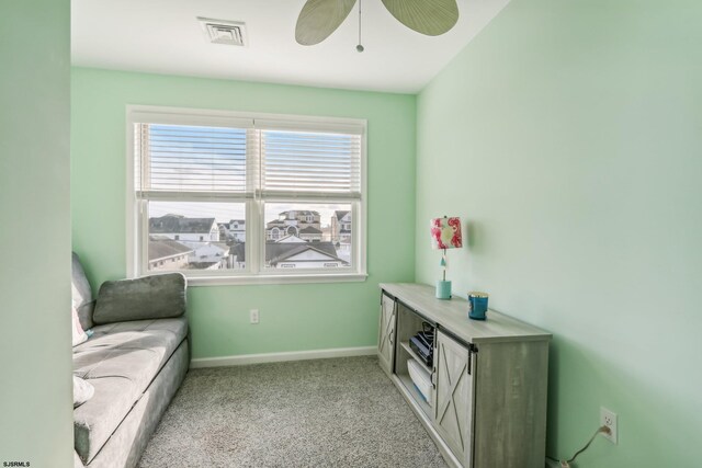 living area featuring light colored carpet and ceiling fan