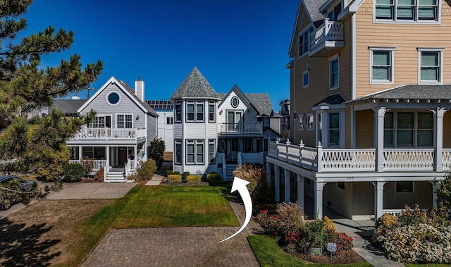 rear view of house featuring a lawn and a balcony