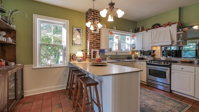 kitchen with kitchen peninsula, a kitchen breakfast bar, hanging light fixtures, stainless steel appliances, and white cabinets