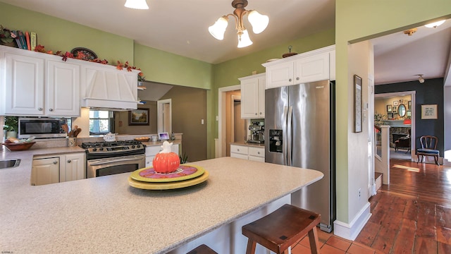 kitchen featuring dark wood-type flooring, stainless steel appliances, white cabinetry, and kitchen peninsula