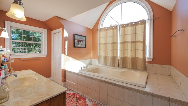 bathroom featuring vanity, vaulted ceiling, and tiled tub