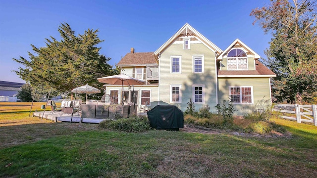 rear view of property featuring a wooden deck and a lawn