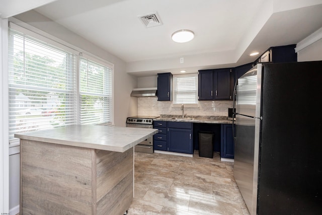 kitchen with backsplash, stainless steel appliances, sink, wall chimney exhaust hood, and blue cabinets