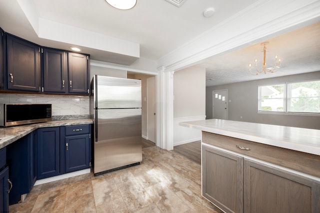 kitchen featuring tasteful backsplash, hanging light fixtures, stainless steel appliances, blue cabinetry, and a chandelier