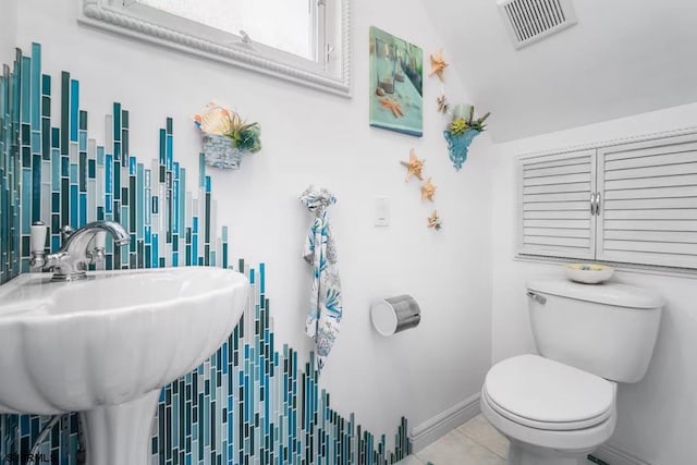 bathroom with tile patterned floors, vaulted ceiling, toilet, and sink