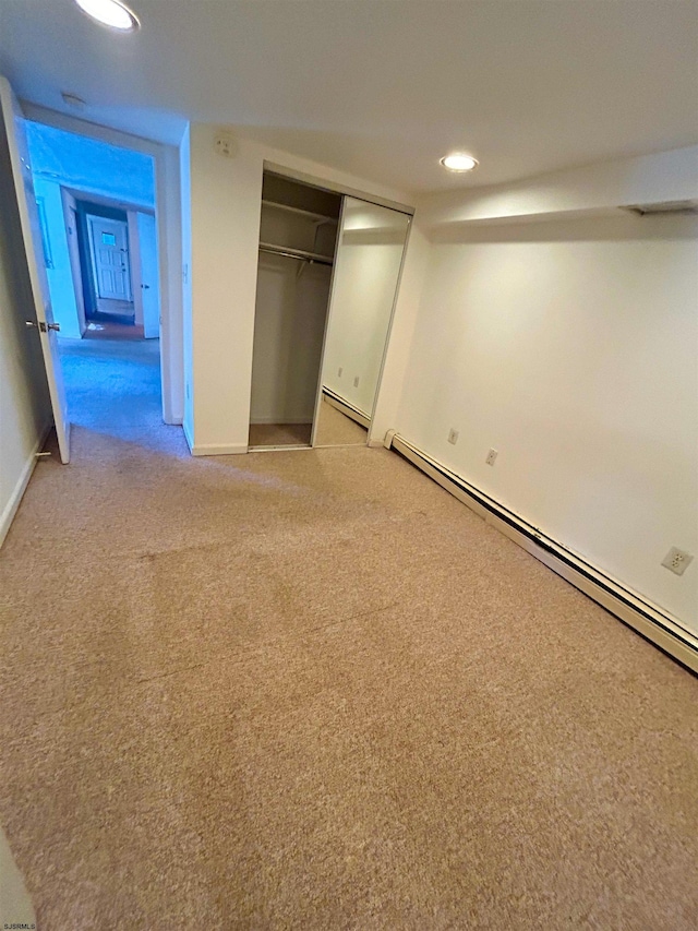 unfurnished bedroom with light carpet, a baseboard radiator, and a closet