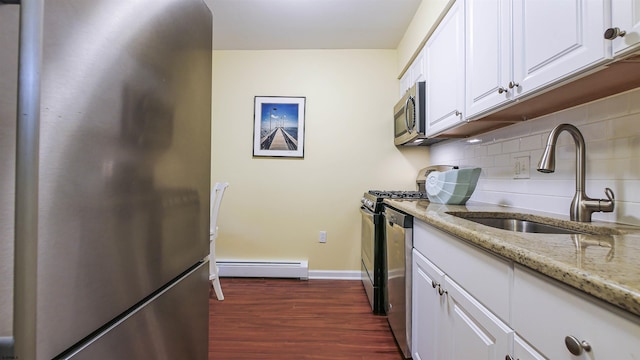 kitchen with light stone countertops, a baseboard heating unit, dark hardwood / wood-style flooring, stainless steel appliances, and white cabinets