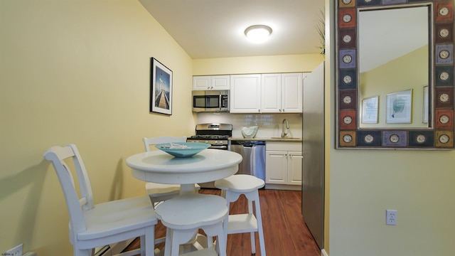 kitchen with dark wood-type flooring, white cabinetry, stainless steel appliances, and backsplash