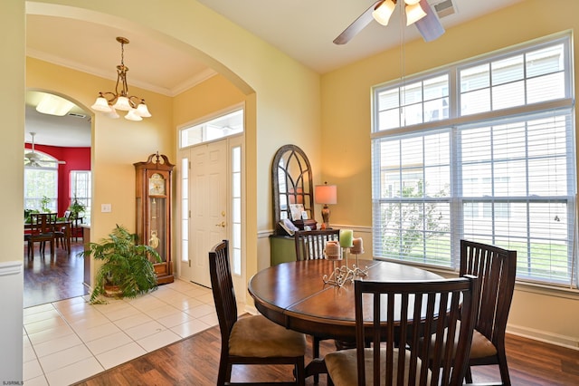 dining area with ornamental molding, a healthy amount of sunlight, ceiling fan with notable chandelier, and light wood-type flooring