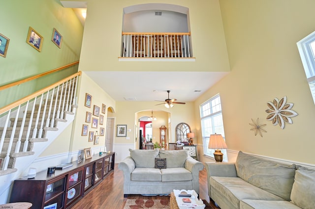 living room with dark wood-type flooring, ceiling fan, and a towering ceiling