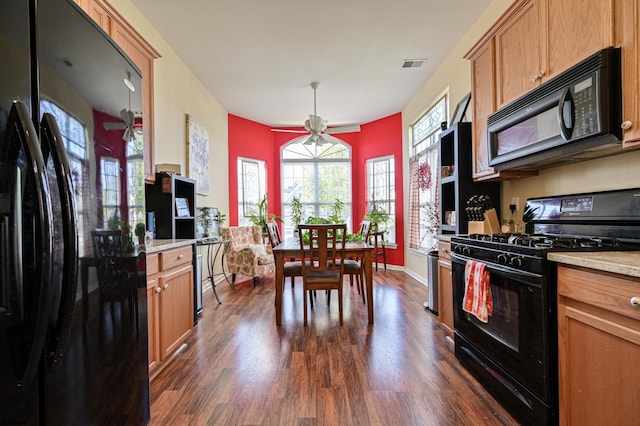 kitchen with ceiling fan, dark hardwood / wood-style flooring, light stone countertops, black appliances, and pendant lighting