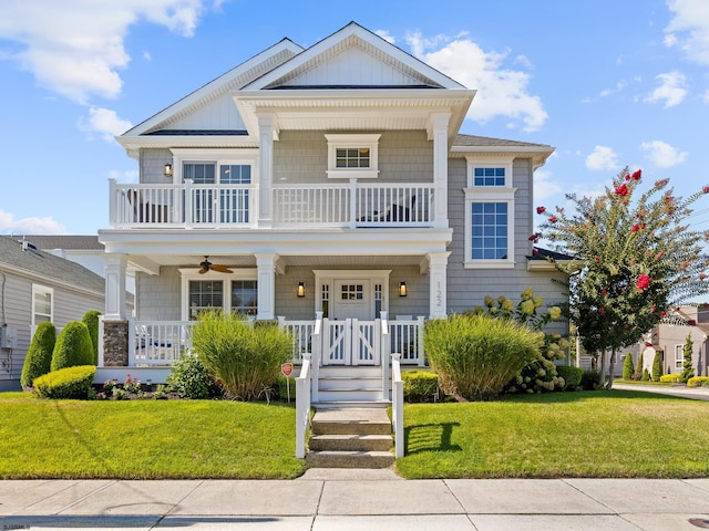 view of front of house featuring covered porch, a front yard, a balcony, and ceiling fan