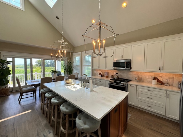 kitchen with white cabinets, a kitchen island with sink, high vaulted ceiling, and stainless steel appliances