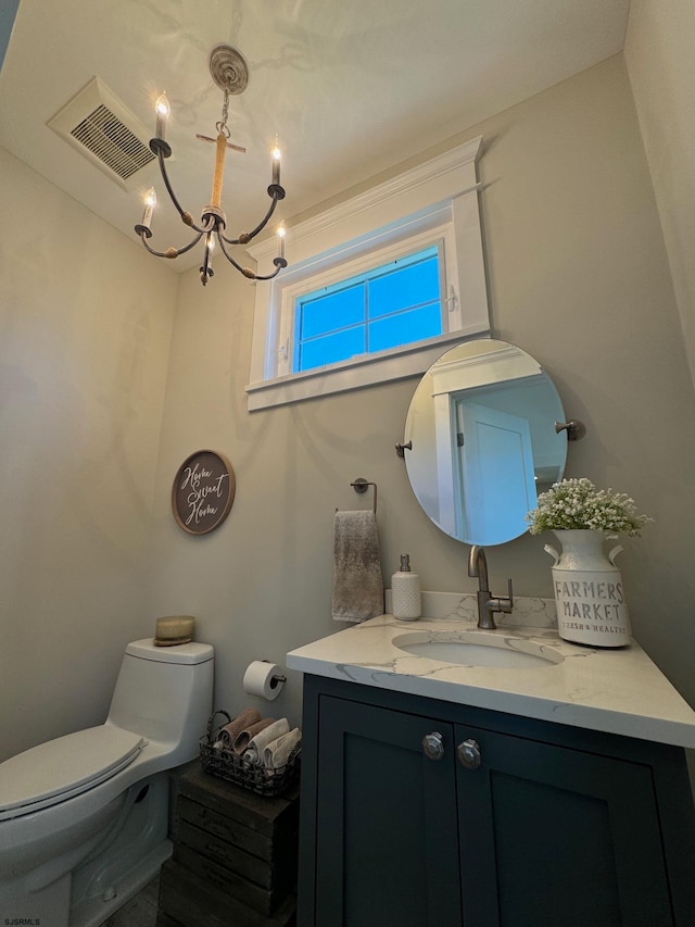 bathroom with vanity, toilet, and an inviting chandelier