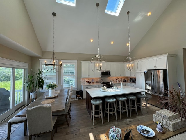 kitchen with a skylight, white cabinetry, high vaulted ceiling, and stainless steel appliances