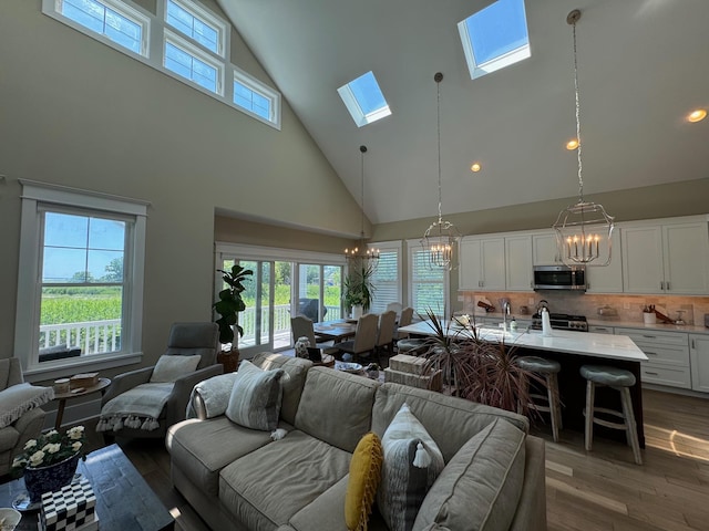 living room with a skylight, a wealth of natural light, high vaulted ceiling, and a chandelier