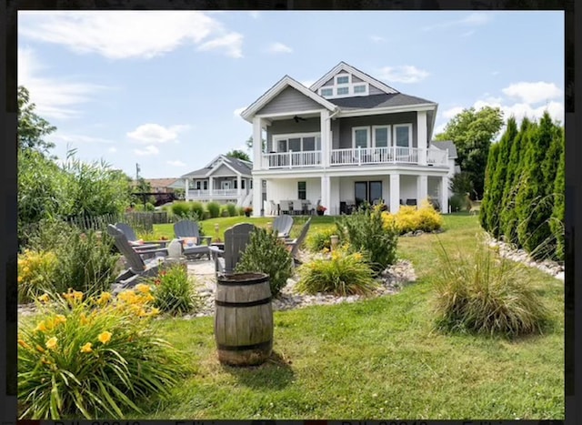 back of house with a yard, a balcony, a fire pit, and ceiling fan