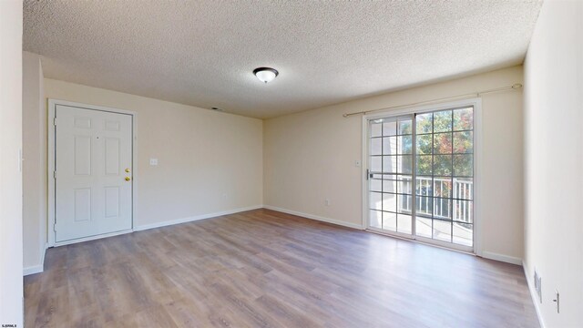 spare room with a textured ceiling and light wood-type flooring