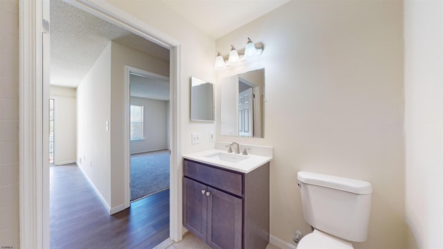 bathroom featuring vanity, toilet, hardwood / wood-style flooring, and a textured ceiling