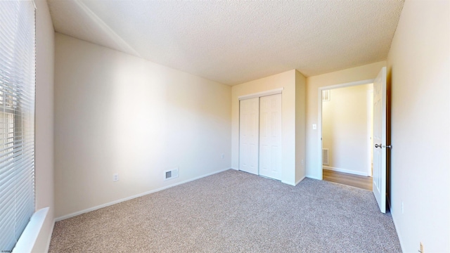 unfurnished bedroom with a closet, carpet floors, and a textured ceiling