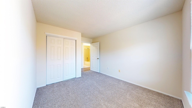 unfurnished bedroom with carpet, a textured ceiling, and a closet