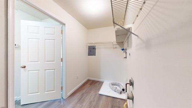 laundry area featuring electric panel and light hardwood / wood-style floors