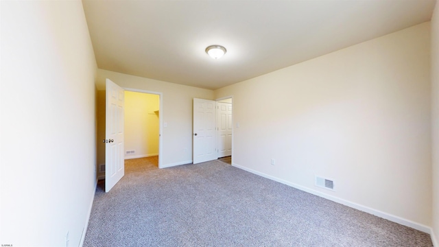 unfurnished bedroom with a closet, a spacious closet, and carpet flooring