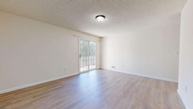 empty room featuring a textured ceiling and light hardwood / wood-style flooring