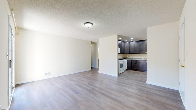 unfurnished living room with light hardwood / wood-style flooring and a textured ceiling