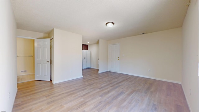 unfurnished room featuring light hardwood / wood-style floors and a textured ceiling