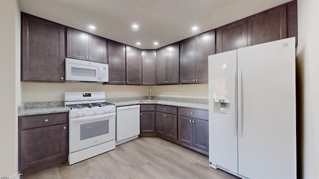 kitchen with sink, light hardwood / wood-style flooring, dark brown cabinets, and white appliances