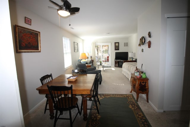 carpeted dining space with ceiling fan