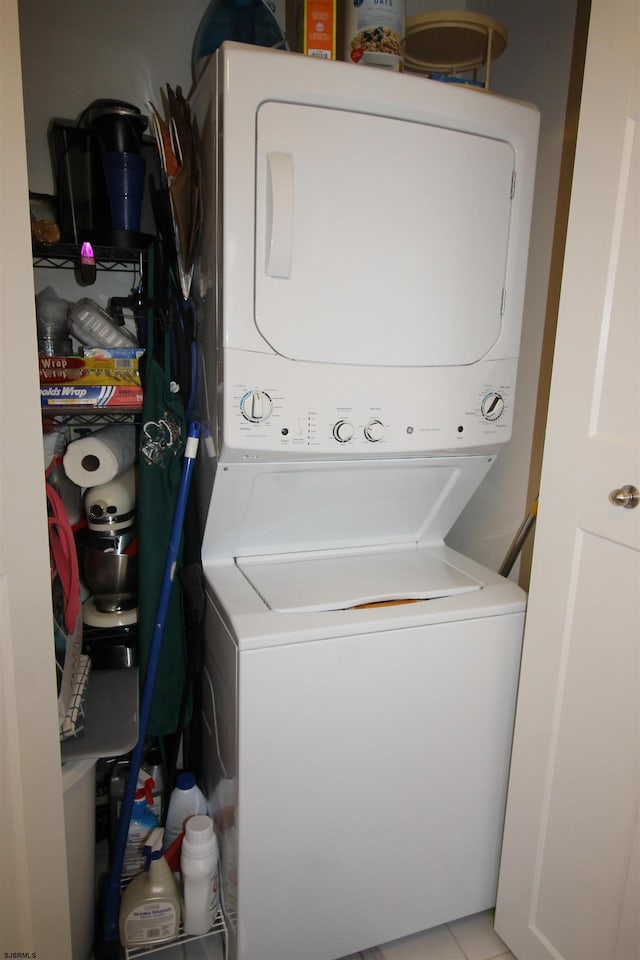 washroom with stacked washer and dryer and light tile patterned floors