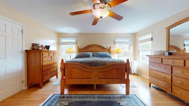 bedroom with radiator, light wood-type flooring, and ceiling fan