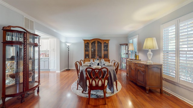 dining space with ornamental molding and hardwood / wood-style floors