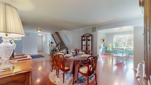 dining room featuring ornamental molding, hardwood / wood-style floors, and an inviting chandelier