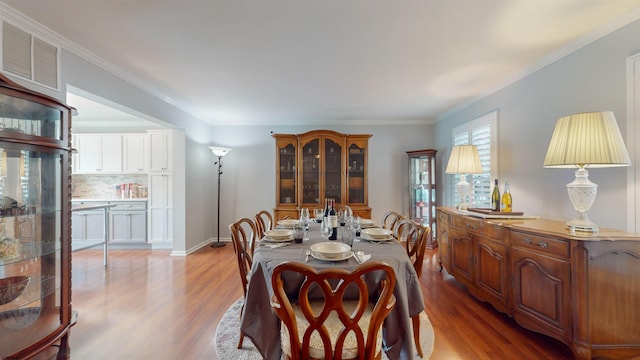 dining area with crown molding and light hardwood / wood-style floors