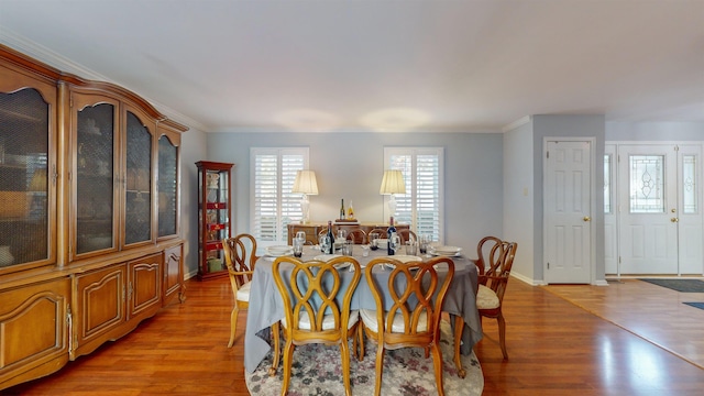 dining room with light hardwood / wood-style floors and crown molding