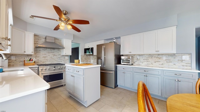 kitchen featuring a kitchen island, wall chimney exhaust hood, sink, white cabinets, and appliances with stainless steel finishes