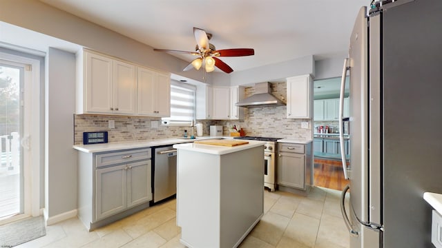 kitchen with wall chimney exhaust hood, stainless steel appliances, backsplash, a center island, and a barn door